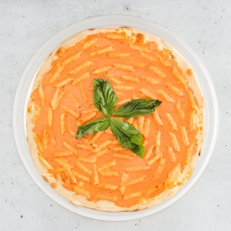 Tita's Pizzeria's vodka sauce pizza, topped with penne pasta and fresh basil leaves.